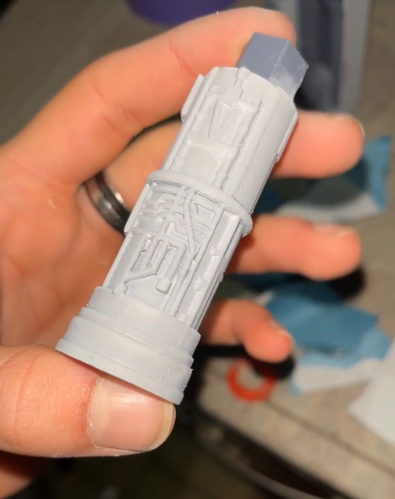 A single printed engine part held between two fingers