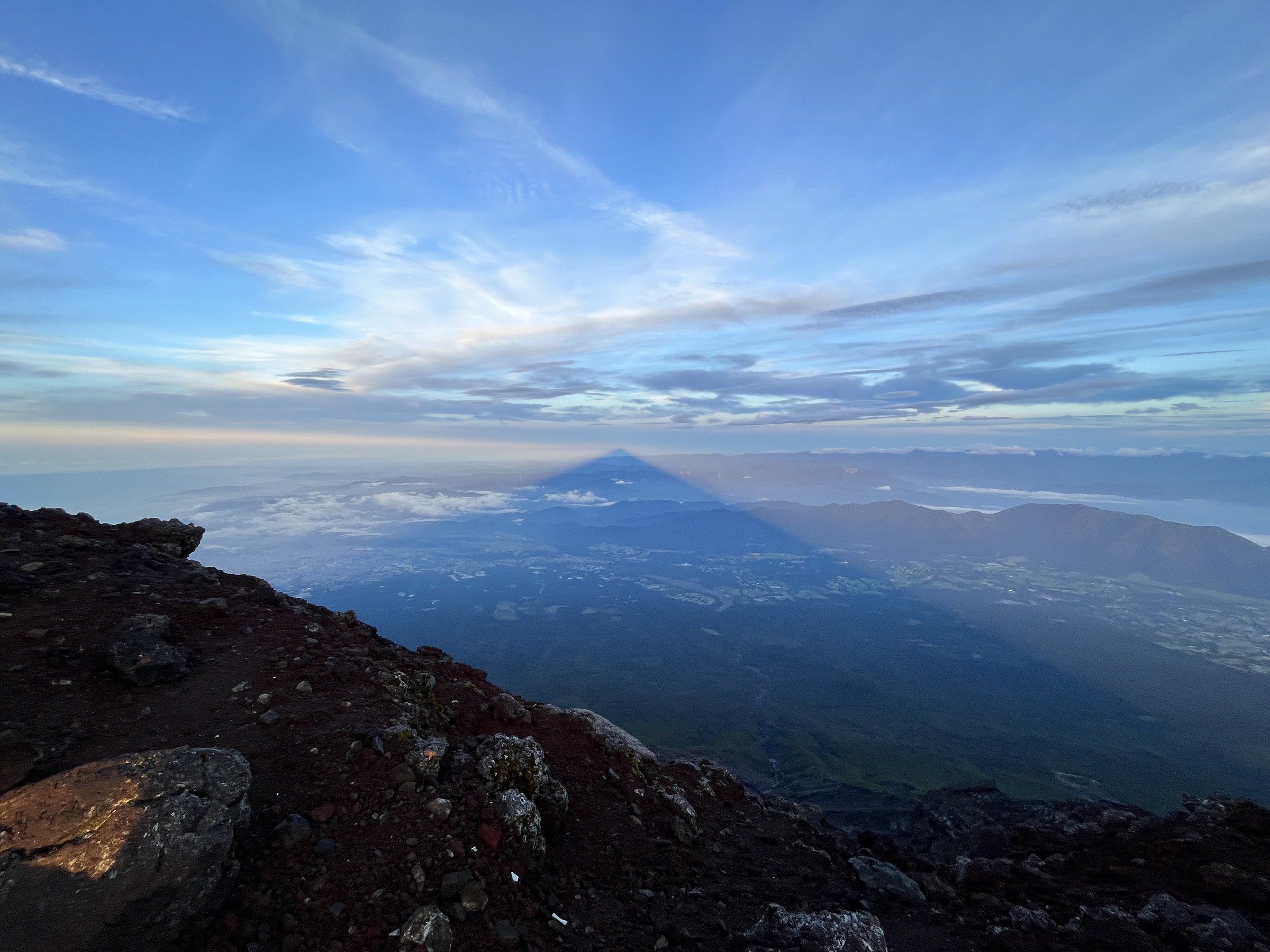 The triangular shadow of Mount Fuji cast across clouds at dawn