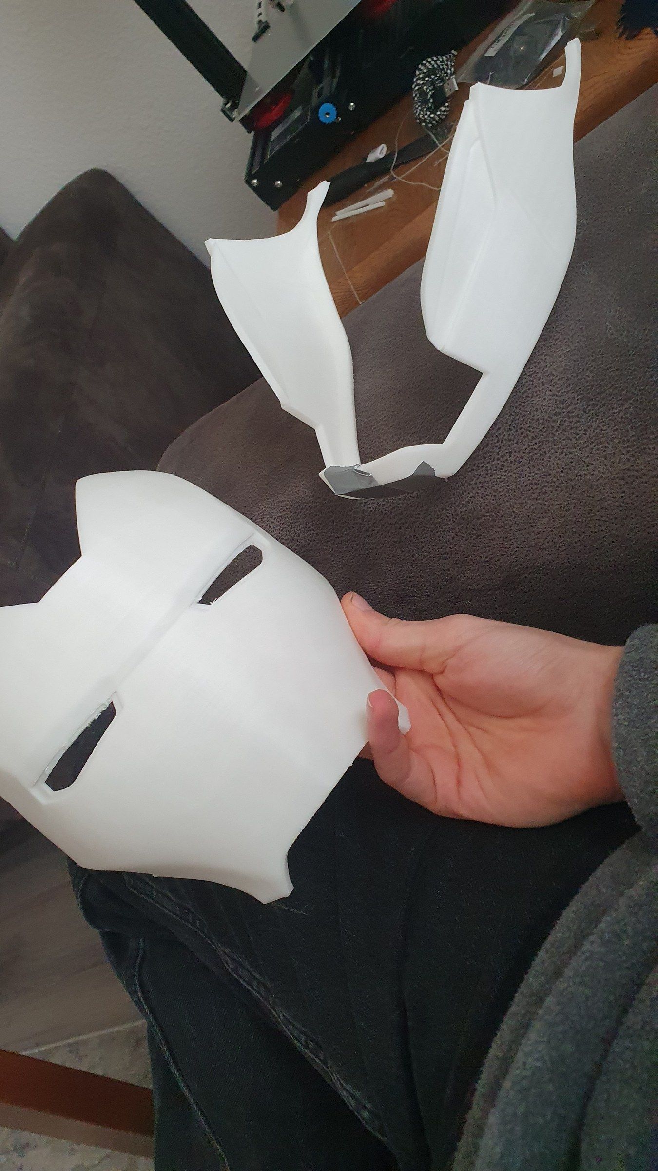 Raw white 3D printed faceplate and cheek parts held in a hand