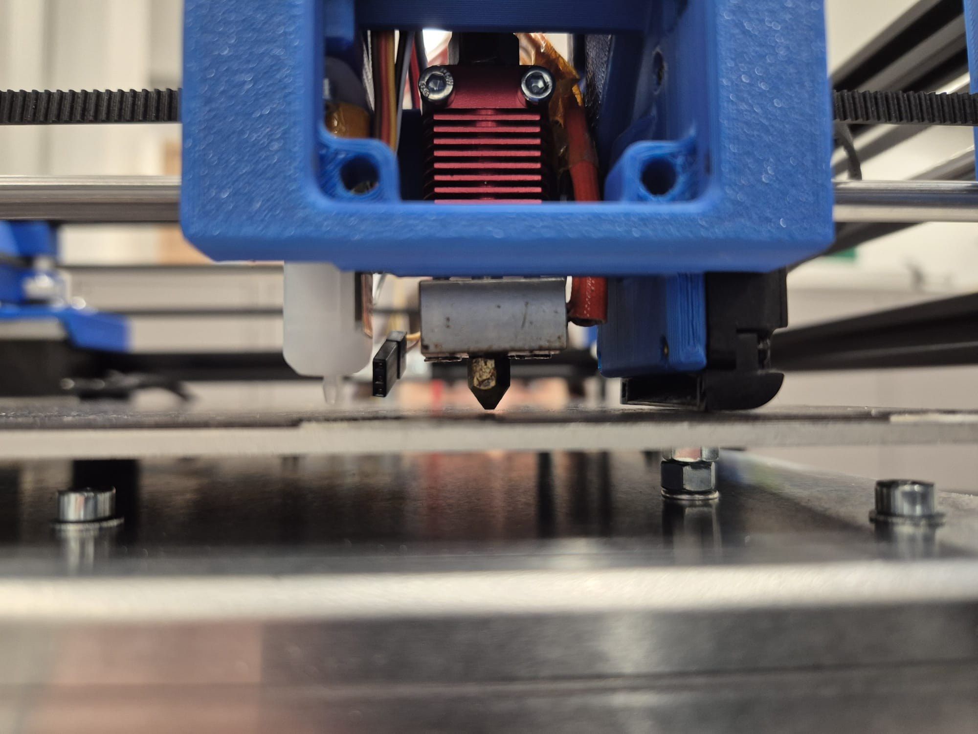 Close-up of the real toolhead with a blue printed shroud above the build plate